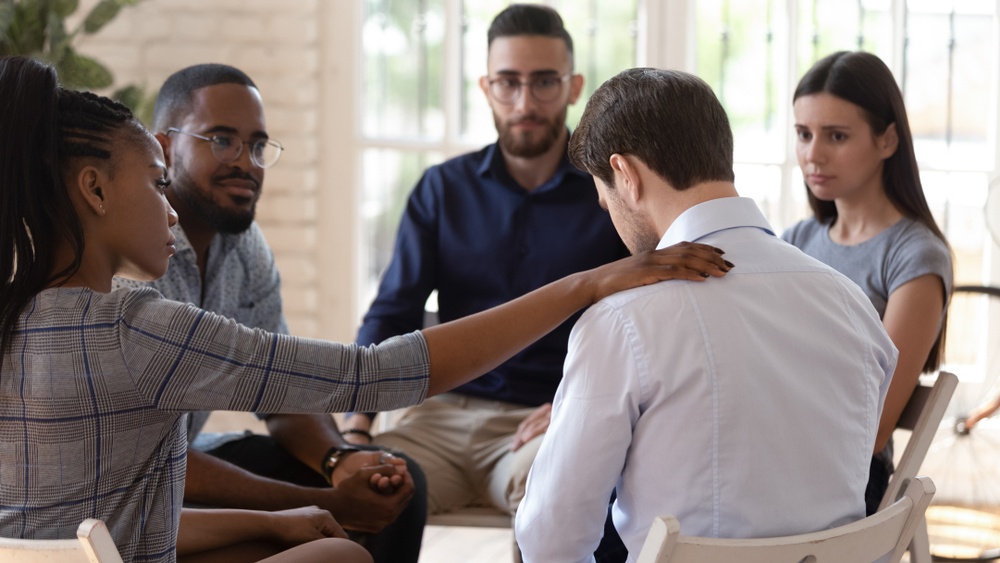 What to Do When You Can't Pray Anymore - get support from others who pray with you - man gets prayer and comfort from group - Shutterstock