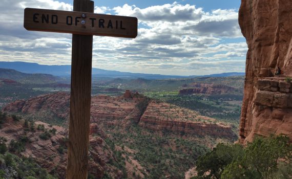 panorama view of the red rock canyons in Sedona - End of Trail sign in the shape of a cross in the forefront