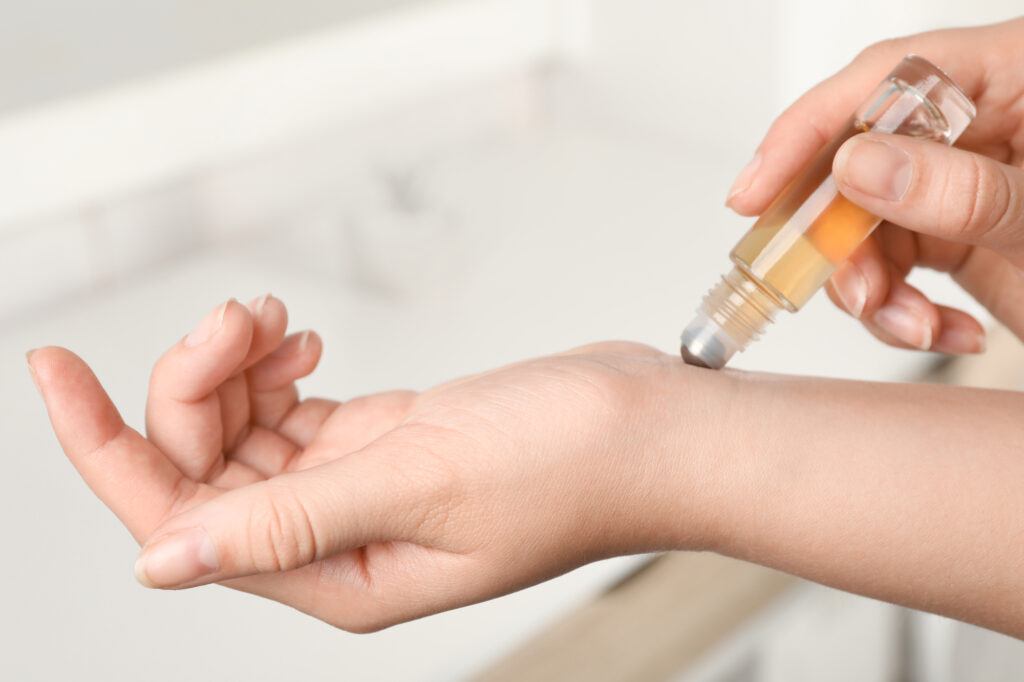 woman applying essential oils on wrist using a rollerball bottle - roller bottle