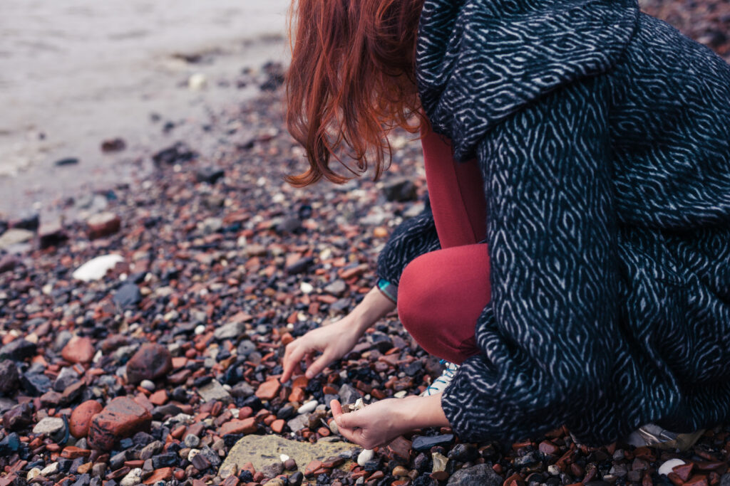 woman picks up shells at a beach