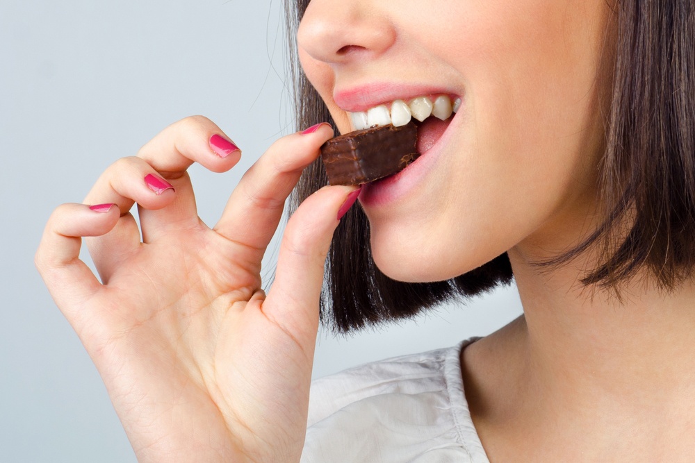 Godiva or Ghirardelli - which is better - woman enjoying a bite of chocolate - Shutterstock