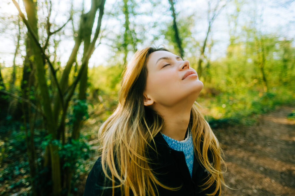 Woman Listening to Nature Sounds with Eyes Closed - iStock 1533215648