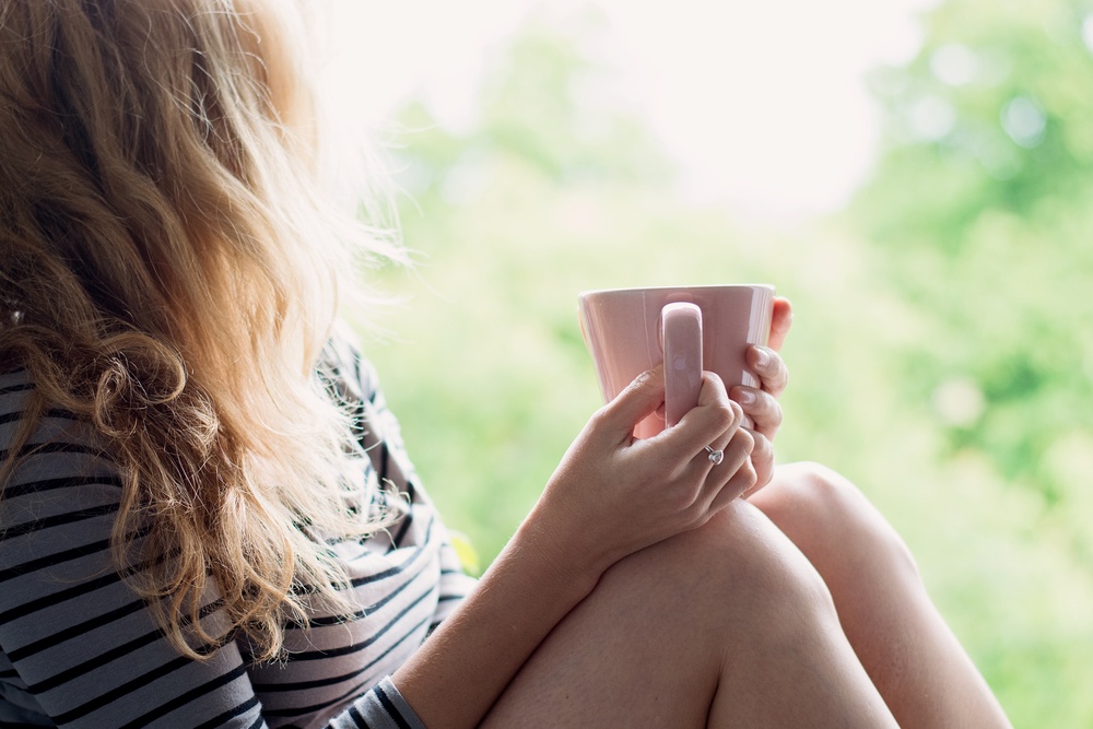 how to be content in life - take joy in simple things - woman relaxing with coffee - Shutterstock