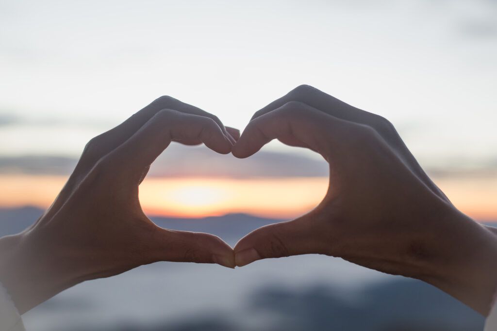 This is God's will for me today -- don't bypass the love relationship in search of the Divine to-do list - hands form a heart shape over the background of setting sun - God's love
