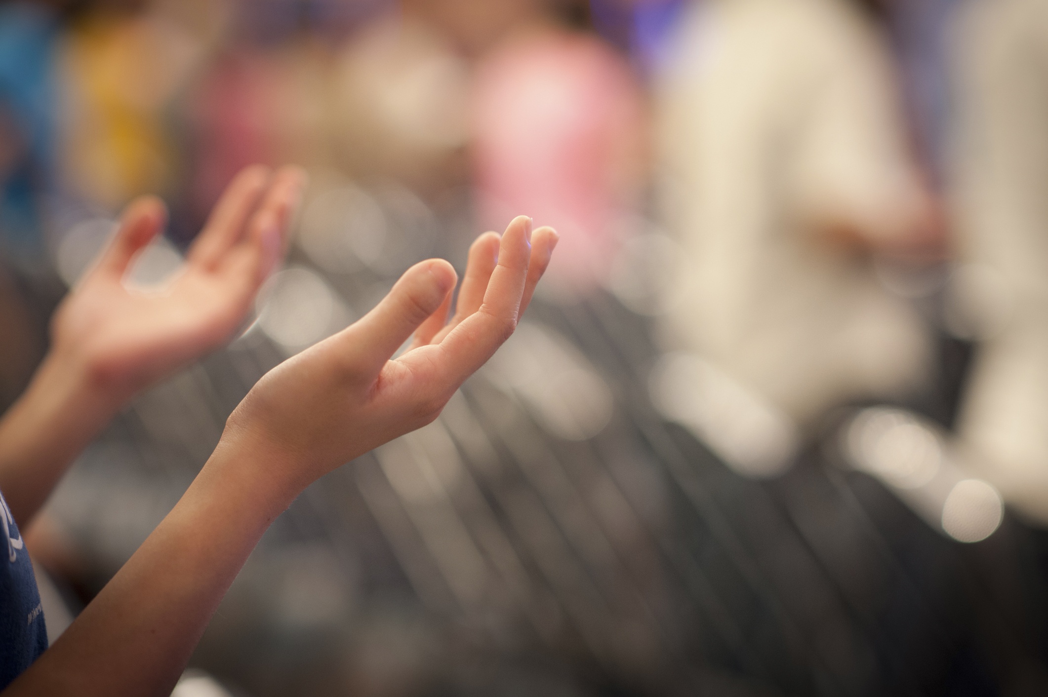 a person's hands lifted in prayer and worship - background is blurry