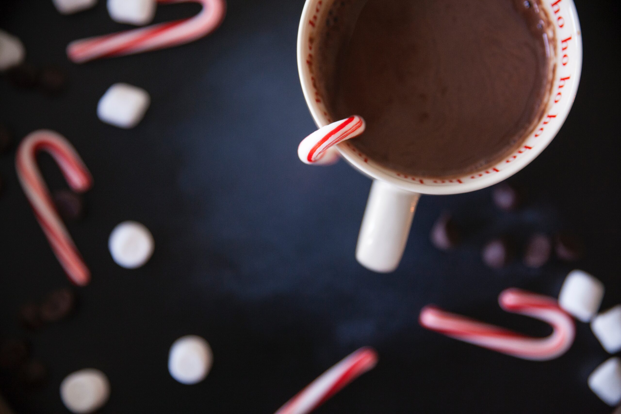 a mug of hot chocolate with a candy cane in it