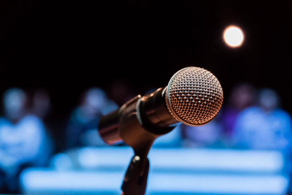 In your season of being anonymous you forgo applause - a microphone on stage with blurred audience