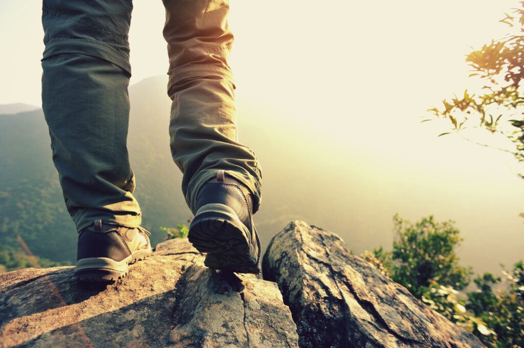 is God leading you somewhere new - a hiker stands on a rocky ridge with sun setting on the wild landscape below