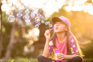Asian girl sitting on the grass and blowing bubbles