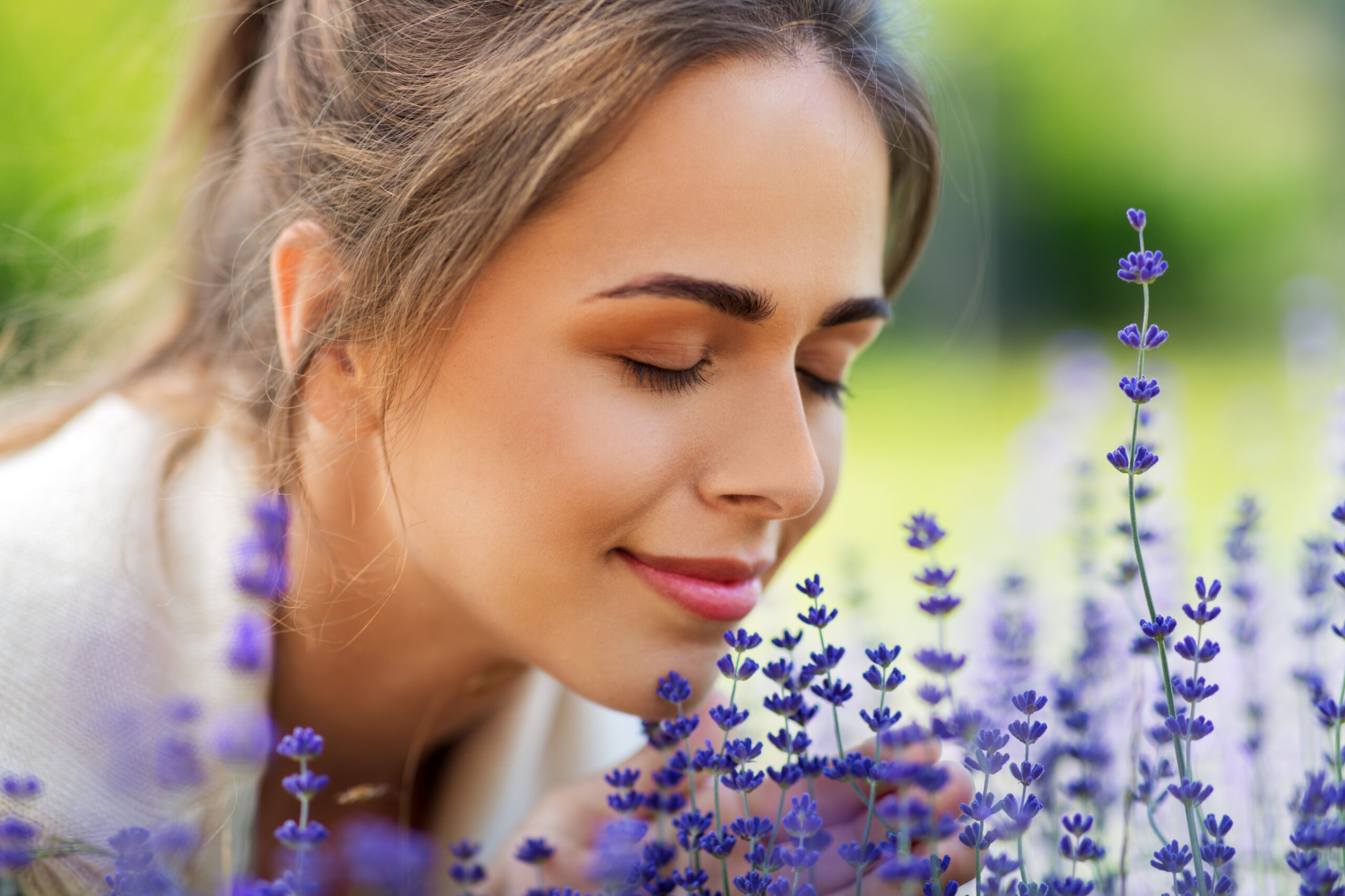 Woman Closes Eyes and Breathes in the Scent from Lavender Blooms