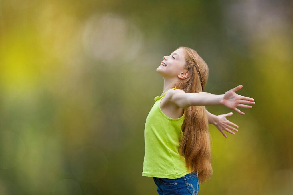 happy little girl praying joyfully in a field