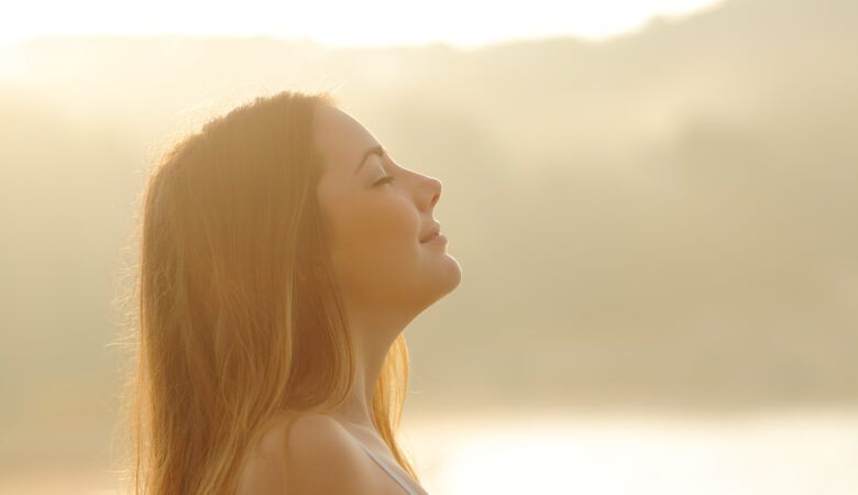 experiencing breath prayer - woman breathes and relaxes with sunset in background