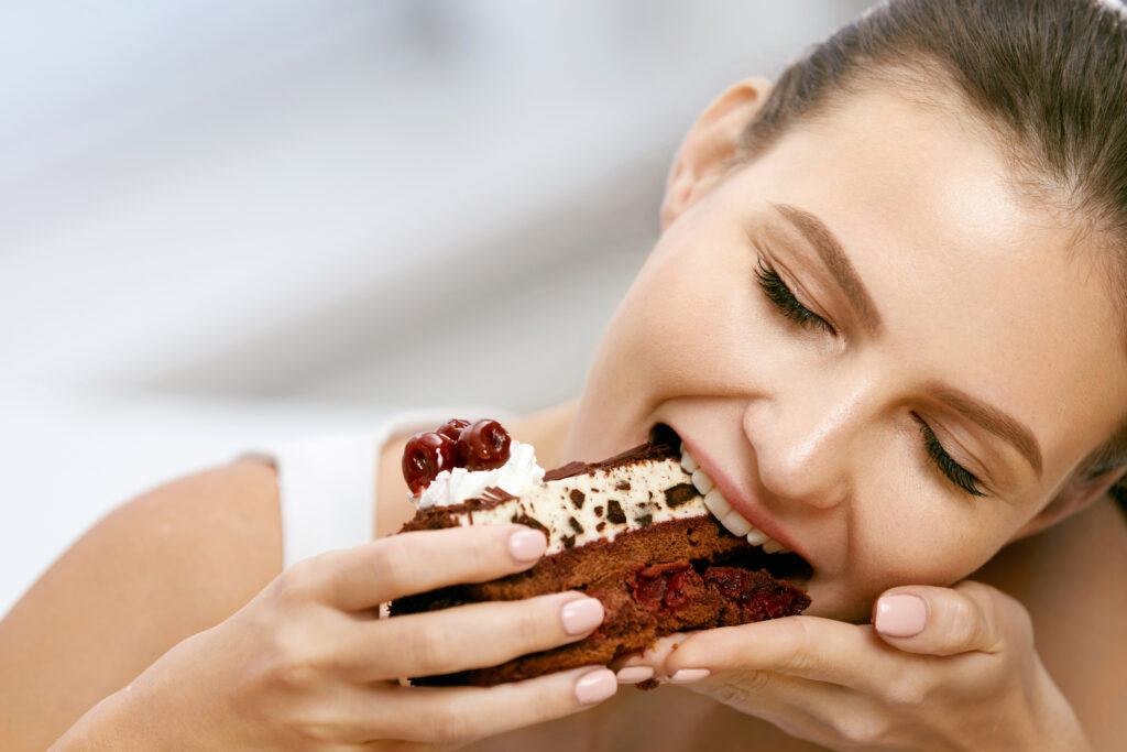 young woman taking a big happy bite of chocolate cake