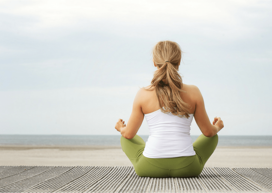 Should Christians Do Yoga - a woman contemplates while in Easy Pose facing the ocean