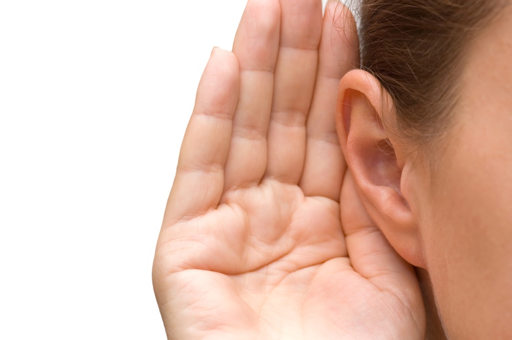 Your Sense of Sound - hearing - woman cups her ear to listen - Shutterstock