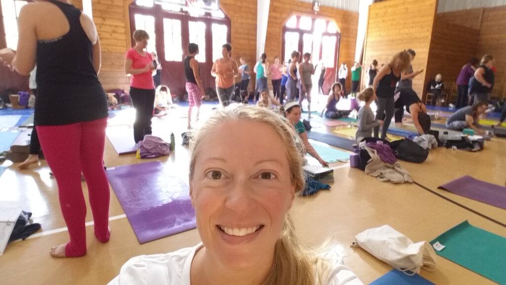 Holy Yoga immersion training answers the question - Should Christians Do Yoga - smiling woman and other women in yoga attire folding up mats afte class