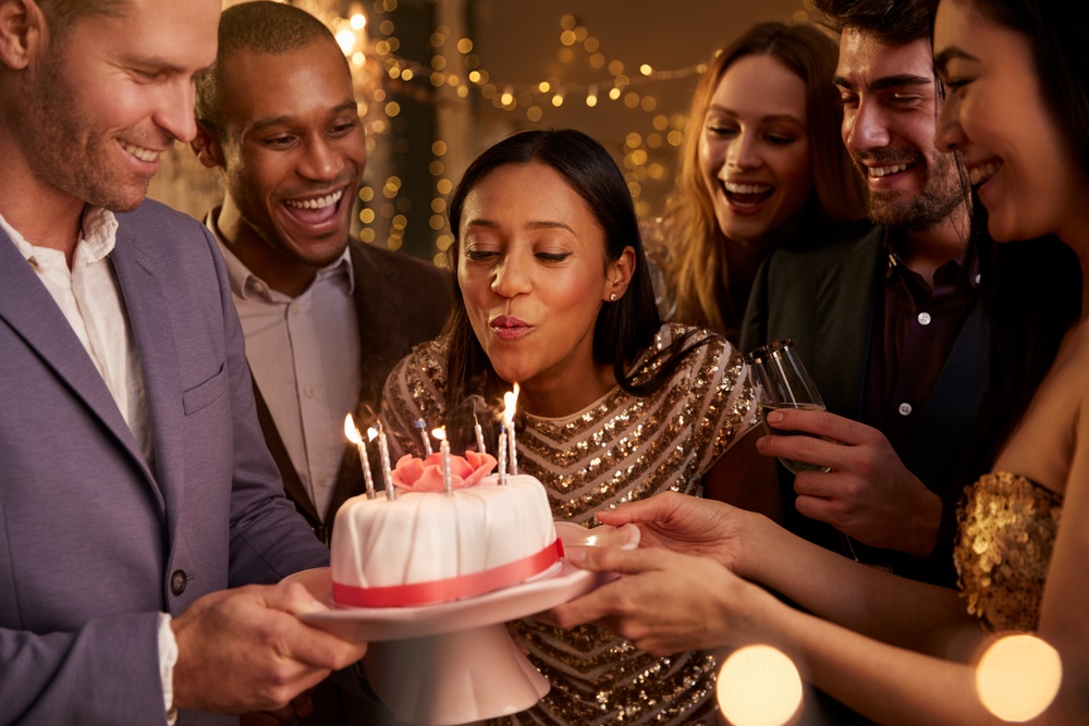 meaningful birthday gift ideas include the celebration of time and relationships - woman surrounded by friends blows out candles