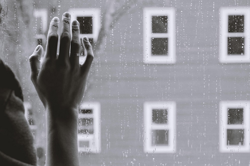 hand on a rainy window pane - grieving the loss of sensory awareness - depression - photo by Kristina Tripkovic - Unsplash