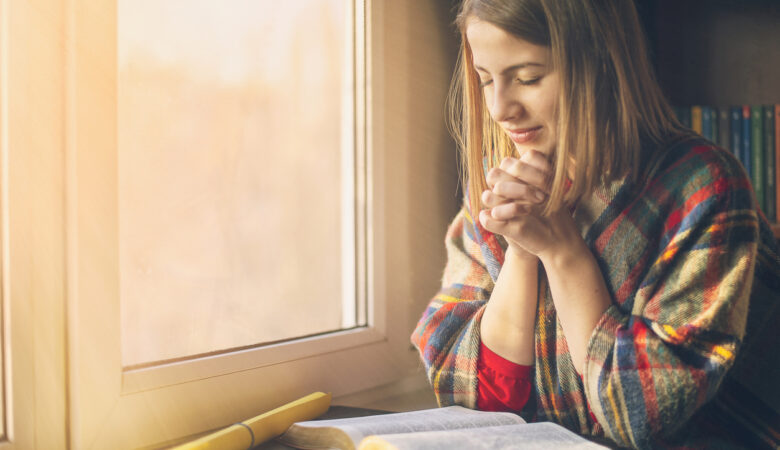 What Should I Pray For - young woman praying with Bible open - photo by Tutye - iStock